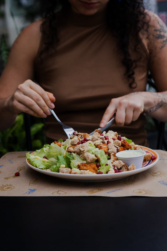 Woman enjoying a fresh salad with lettuce and croutons outdoors, emphasizing healthy eating